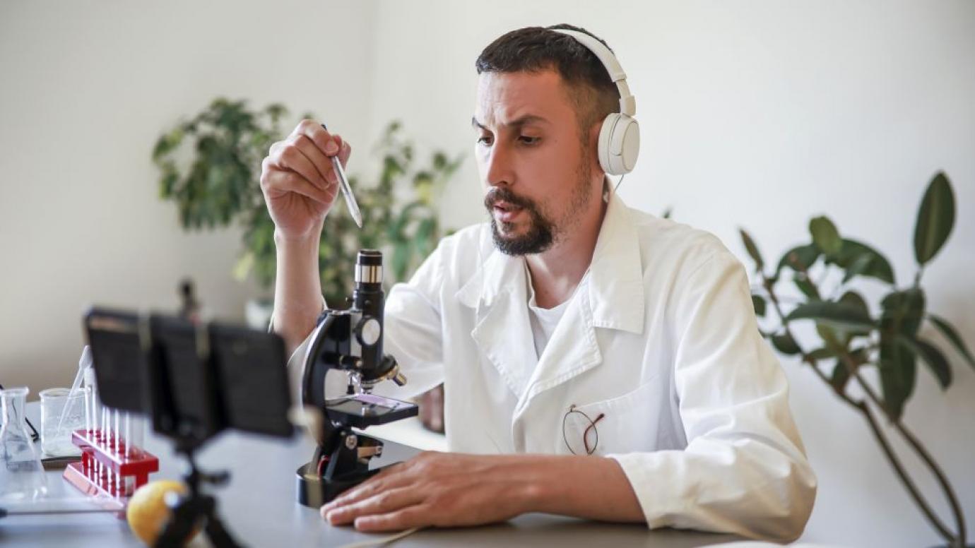 Scientist with microscope and smart phone in foreground