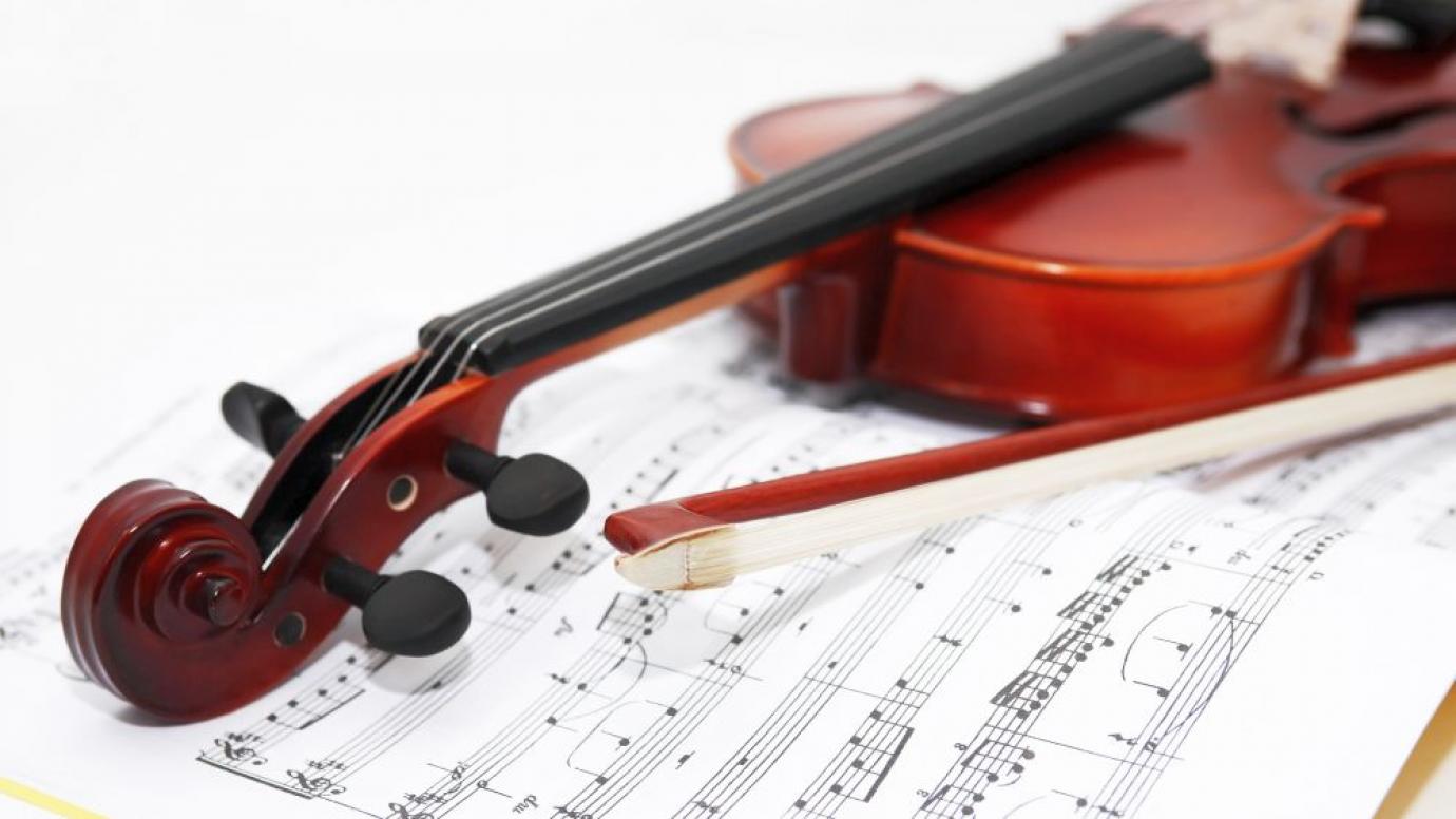 A violin resting on some sheet music