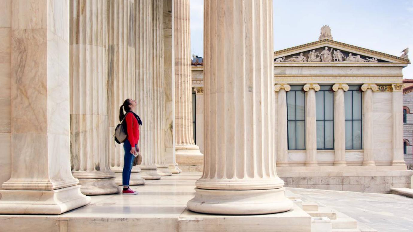 Student looks up at columns of academic building