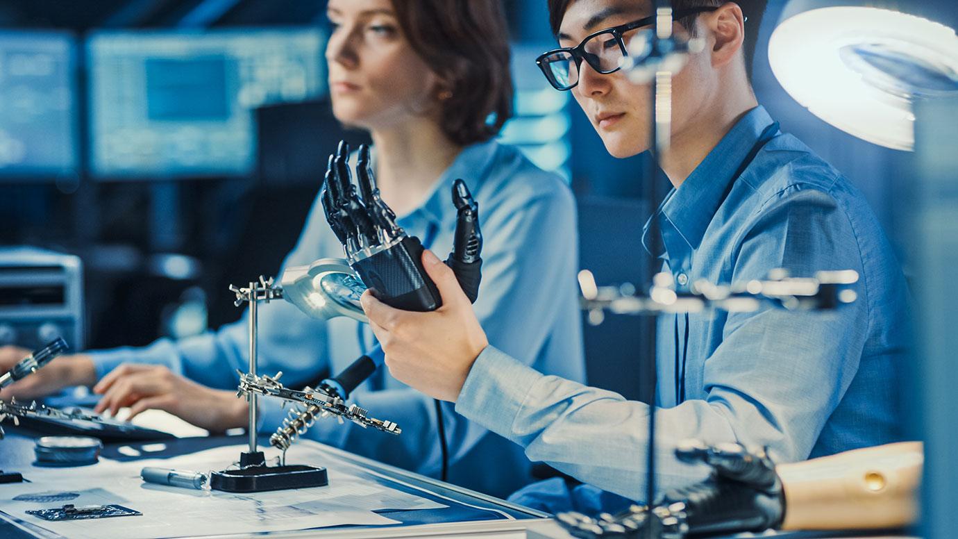 Two engineers testing a prosthetic robot arm in a research lab