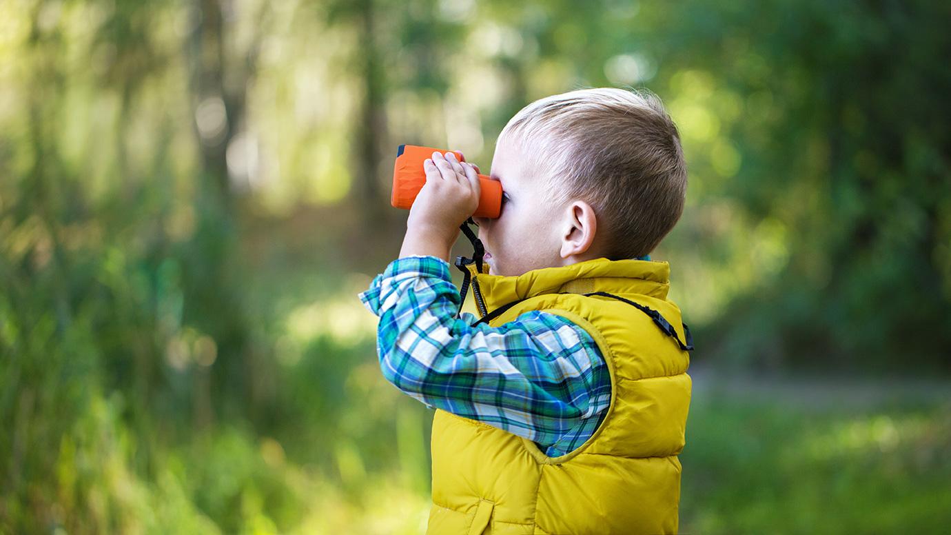 Young boy exploring nature with binoculars
