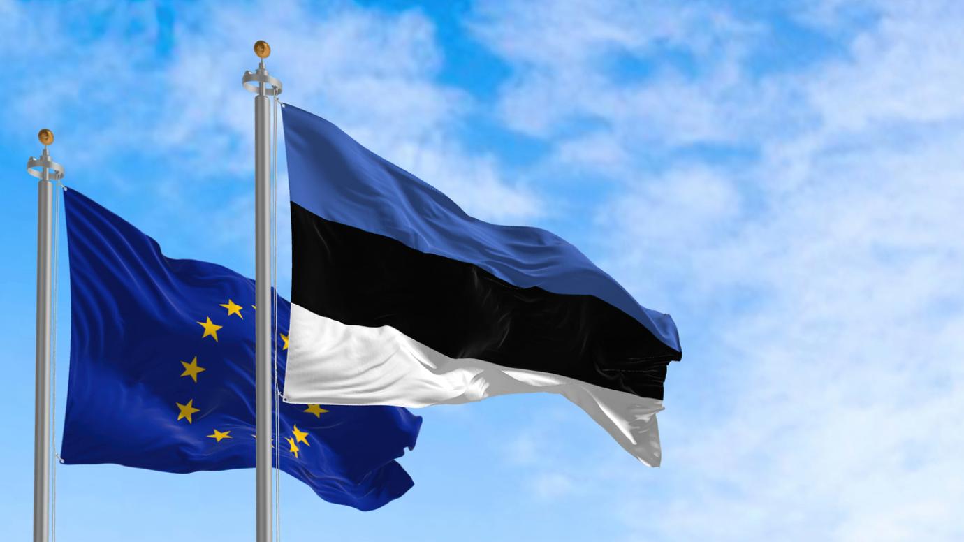 The flags of Estonia and the European Union waving together on a clear day.